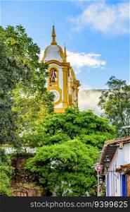 Baroque church tower rising through vegetation and buildings in the city of Tiradentes in the state of Minas Gerais. Baroque church tower rising through vegetation