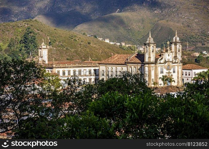Baroque churches in Ouro Preto between the vegetation and mountains of the city. Historic baroque churches in Ouro Preto
