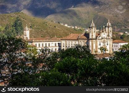 Baroque churches in Ouro Preto between the vegetation and mountains of the city. Historic baroque churches in Ouro Preto