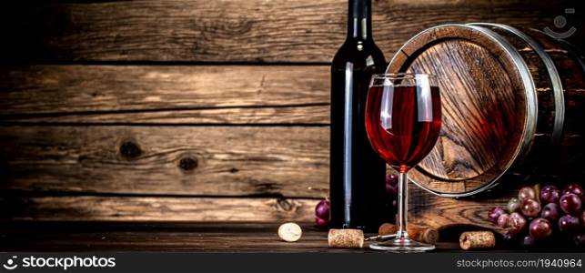 Barrel, a bottle and a glass of red wine. On a wooden background. . Barrel, a bottle and a glass of red wine.