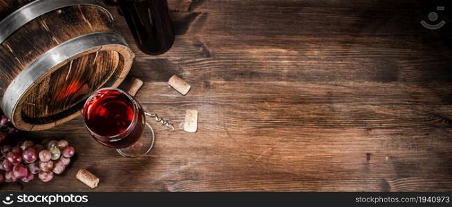 Barrel and a glass of red grape wine. On a wooden background. . Barrel and a glass of red grape wine.
