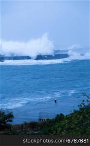 Barrier wall at beach with crashing waves during storm