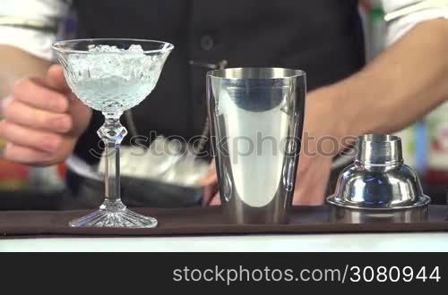 Bartender, barman is making delicious cocktail at bar counter using ice and sweet liquor, and making tricks, shots