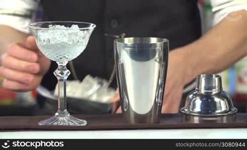 Bartender, barman is making delicious cocktail at bar counter using ice and sweet liquor, and making tricks, shots