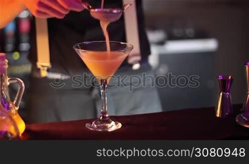 Bartender, barman is making delicious cocktail at bar counter using ice and sweet liquor, and making tricks, shots