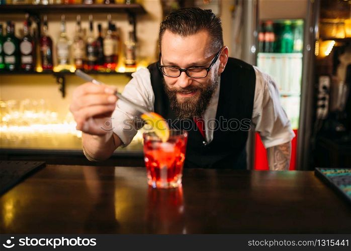 Bartender behind bar counter making alcohol coctail in restaurant. Bartender making alcohol coctail in restaurant