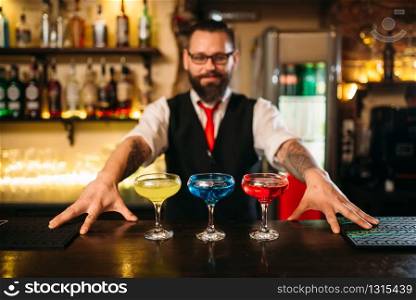 Bartender behind bar counter show alcohol coctails in restaurant