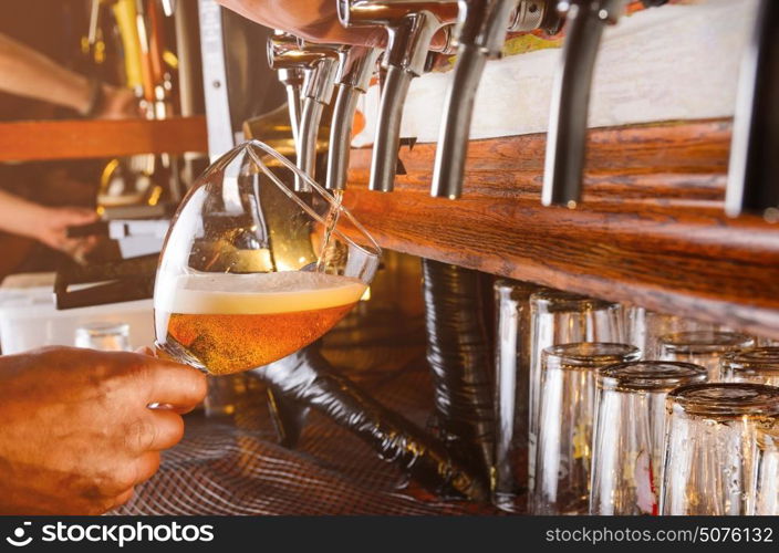 Bartender hand pouring draught beer to glass from a pub tap. Barman is serving beer from faucet