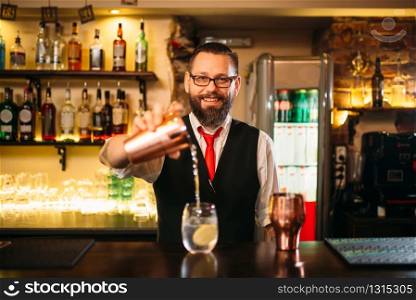 Bartender is making alcohol cocktail at bar counter. Barman with shaker