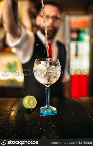 Bartender pouring alcoholic drink in glass. Barman flairing with alcoholic cocktail. Bartender pouring alcoholic drink in glass