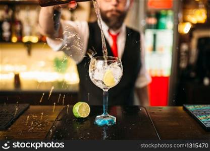 Bartender pouring alcoholic drink in glass. Barman flairing with alcoholic cocktail