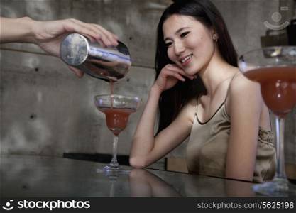 Bartender serving a cocktail to a young woman