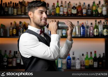 Bartender shaking cocktail shaker in cocktail bar. High quality photo. Bartender shaking cocktail shaker in cocktail bar