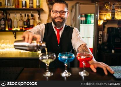 Bartender with shaker making alcohol beverages behind a bar counter in nightclub. Bartender making alcohol beverages in nightclub