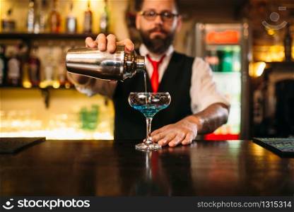 Bartender with shaker making alcohol cocktail behind a bar counter. Bartender with shaker making alcohol cocktail