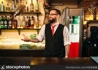 Bartender with shaker show trick behind a bar counter. Modern club nightlife
