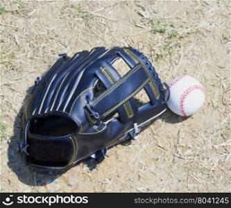 Baseball and glove over dirt, horizontal image
