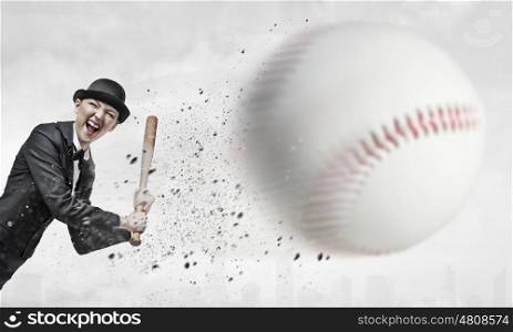 Baseball girl training. Young woman in suit and cylinder hitting ball with baseball bat