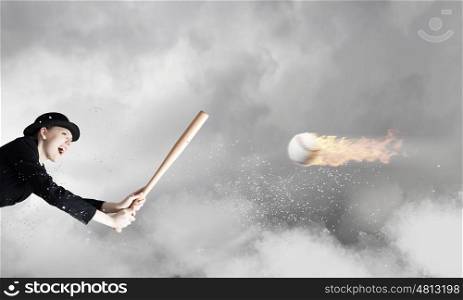 Baseball girl training. Young woman in suit and cylinder hitting ball with baseball bat