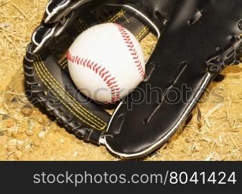 Baseball in glove over dirt, horizontal image