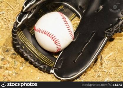 Baseball in glove over dirt, horizontal image
