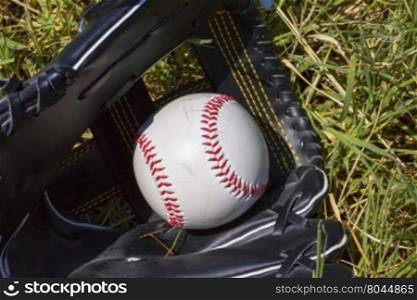 Baseball in glove over grass, horizontal image