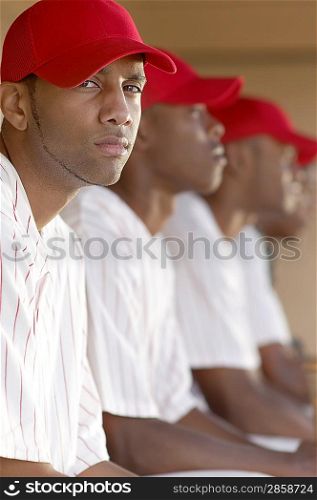 Baseball Player Sitting in Dugout with Team