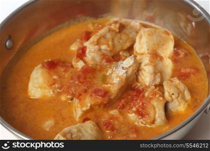 Basic fish curry, in a spicy tomato and coconut milk sauce, in a kadai (karahi or wok) serving bowl, close-up