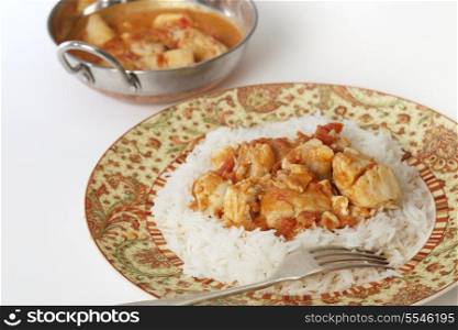 Basic fish curry, in a spicy tomato and coconut milk sauce, served on a bed of basmati rice, with a kadai (or karahi or wok) serving bowl.