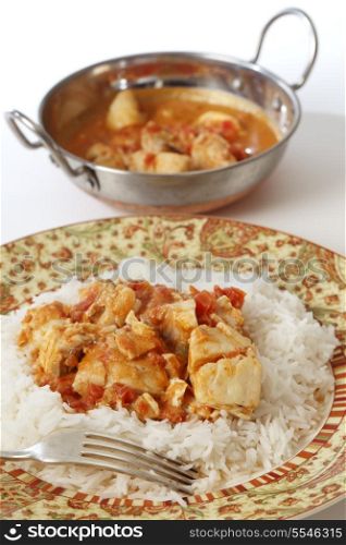Basic fish curry, in a spicy tomato and coconut milk sauce, served on a bed of basmati rice, with a kadai (karahi or wok) serving bowl inthe background