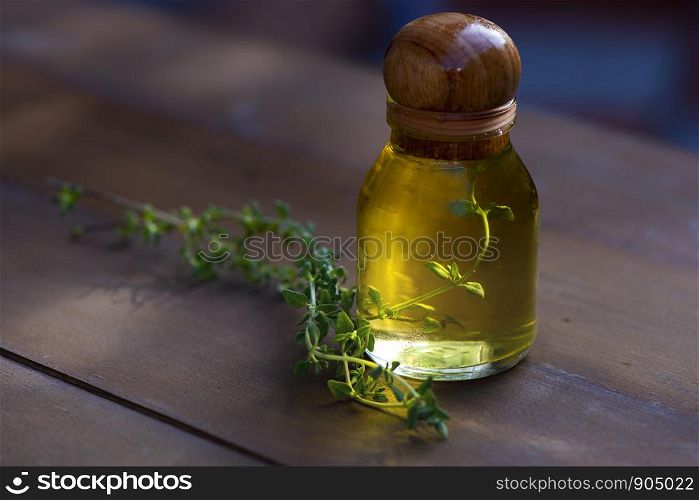 Basil Essential Oil In a bottle with fresh basil branches And the golden light shining from the back of the bottle Lay on the wooden floor