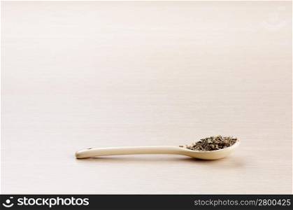 Basil in a spoon over a blured wooden background with copy space