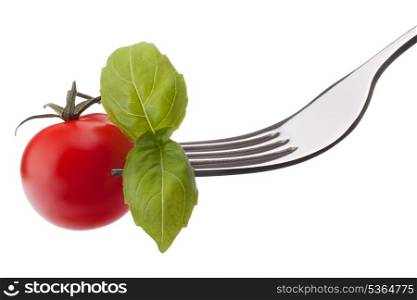 Basil leaf and cherry tomato on fork isolated on white background cutout. Healthy eating concept.