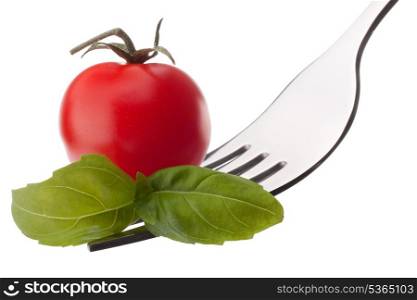 Basil leaf and cherry tomato on fork isolated on white background cutout. Healthy eating concept.