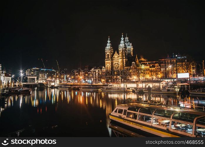 Basiliek van de Heilige Nicolaas in Amsterdam. View from river canal at dusk time with boats