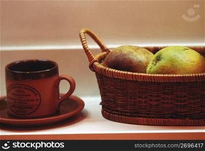 basket of apples next to cup