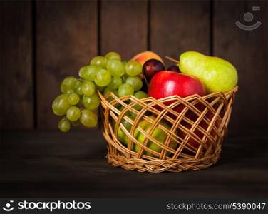 Basket of fruits on wood background closeup