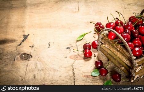 basket of red cherry and leaves . On a wooden table.. basket of red cherry and leaves .