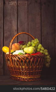 Basket of vegetables and fruits over wooden background