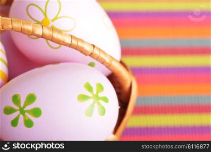 basket wicker with decoration easter eggs on striped napkin