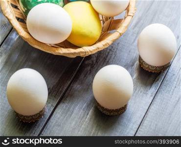 Basket with colorful easter eggs and flower on wooden table
