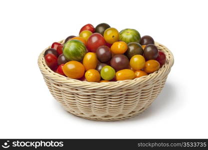 Basket with different color homegrown organic tomatoes on white background