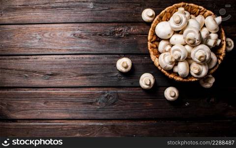 Basket with fresh mushrooms. On a wooden background. Top view. High quality photo. Basket with fresh mushrooms. On a wooden background.