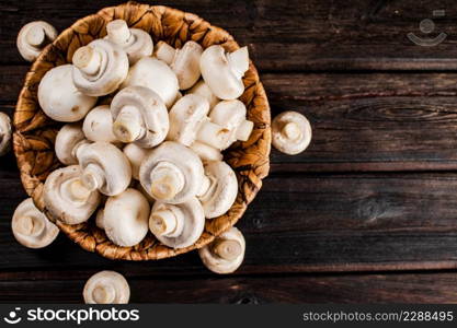 Basket with fresh mushrooms. On a wooden background. Top view. High quality photo. Basket with fresh mushrooms. On a wooden background.