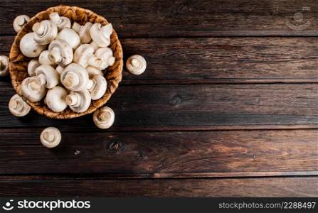 Basket with fresh mushrooms. On a wooden background. Top view. High quality photo. Basket with fresh mushrooms. On a wooden background.