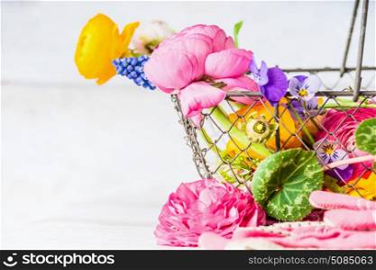 Basket with pretty garden flowers at white wooden background, close up