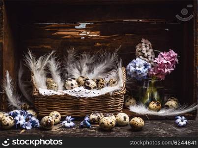 Basket with quail eggs and feathers and spring flowers Hyacinths bunch on vintage wooden table, over rustic background, side view. Easter greeting card