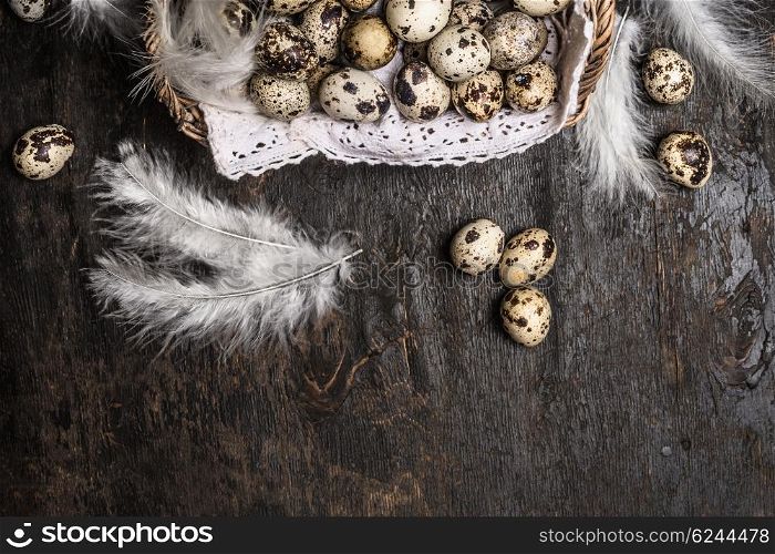 Basket with quail eggs and feathers on rustic wooden background, top view, horizontal