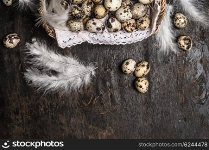 Basket with quail eggs and feathers on rustic wooden background, top view, horizontal