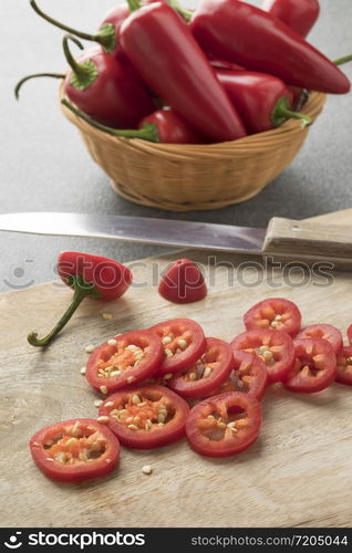 Basket with red Jalapeno peppers and slices close up on a cutting board